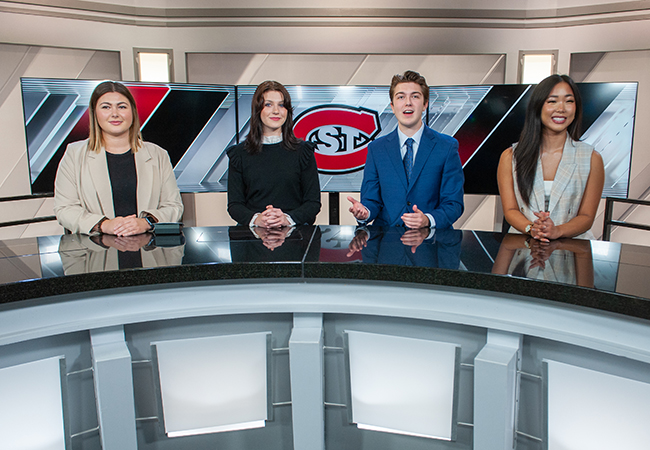 Four student broadcasters seated at news desk