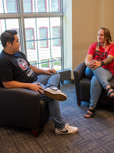 Two students seated in empty therapy room