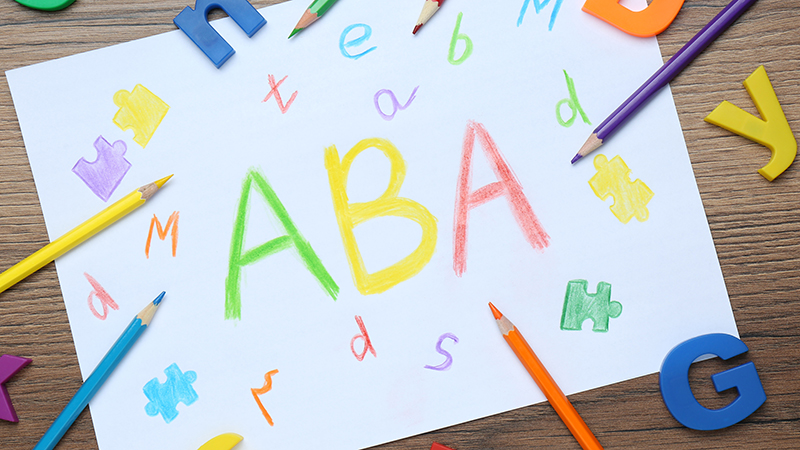 Kid's drawing of "ABA" with crayons laying on the table