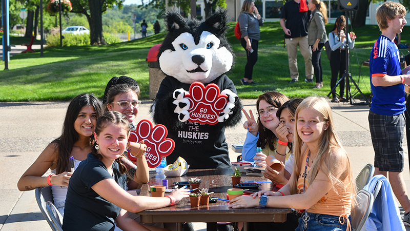 Several students at outdoor picnic table smiling for a photo with Blizzard