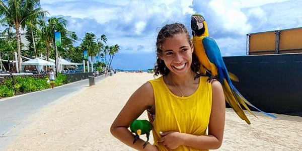 Parrot on shoulder alongside beach