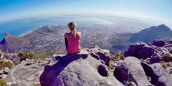 Student sitting on mountain looking into horizon