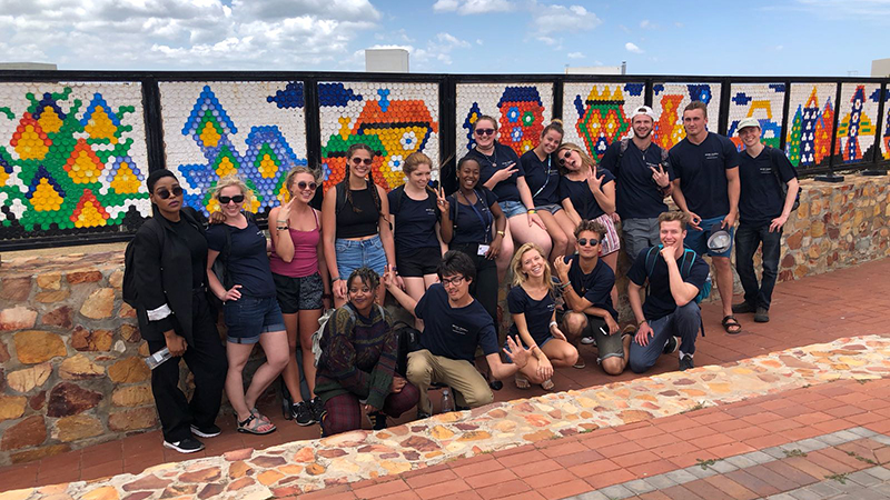 Group photo in front of a mosaic wall