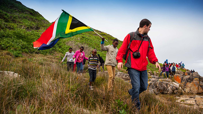Walking on hillside with South African flag