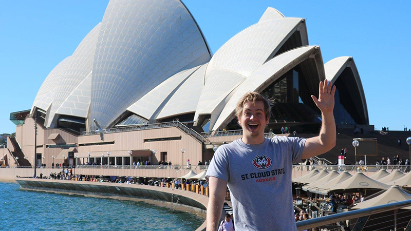 Student waving in front of Sydney Opera House
