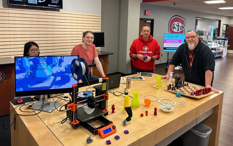 People Near Table of 3D Printer and Items