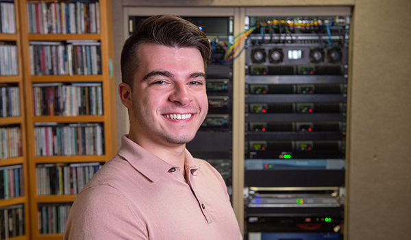 Male student smiling with racks of CDs in background