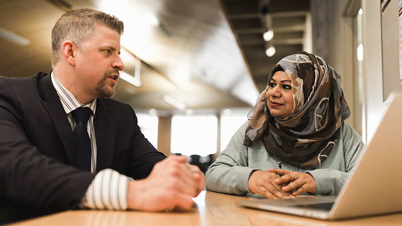 Two people seated at table talking