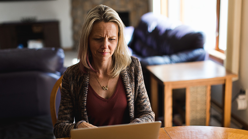 Woman working on laptop in home kitchen