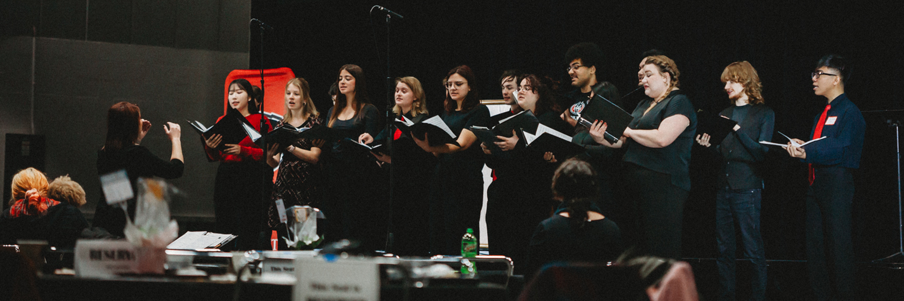 Small choir dressed in black singing on stage