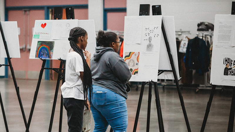 Two young women looking at artwork on easels