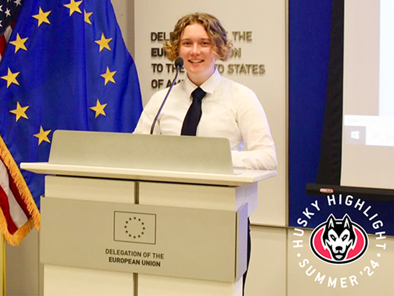 Student in dress shirt and tie standing at podium of the Delegation of the European Union