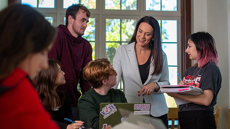 Staff person engaging with students around table