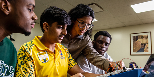 Computer science students gathered around equipment on desk