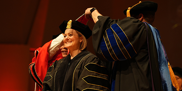 Woman receiving doctoral hood at ceremony