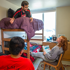 Three students hanging out in dorm room