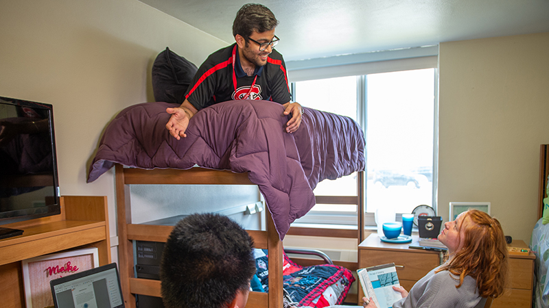 Three students hanging out in dorm room