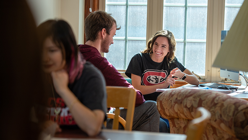 Student smiling kindly at another while working on homework