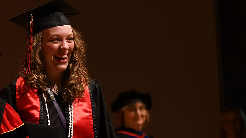 Graduate smiling on Commencement stage