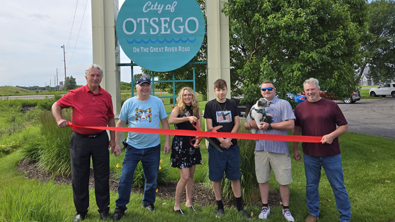 Ribbon cutting ceremony with six people and a dog