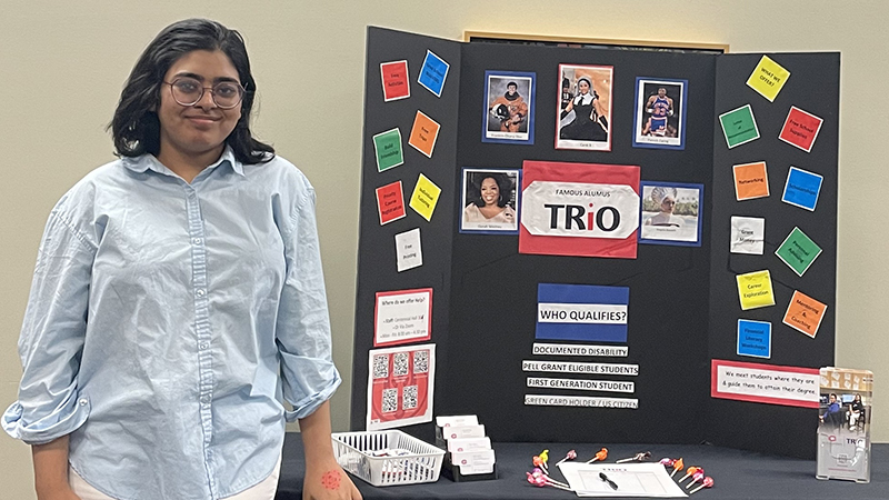 TRIO student standing by tabling display