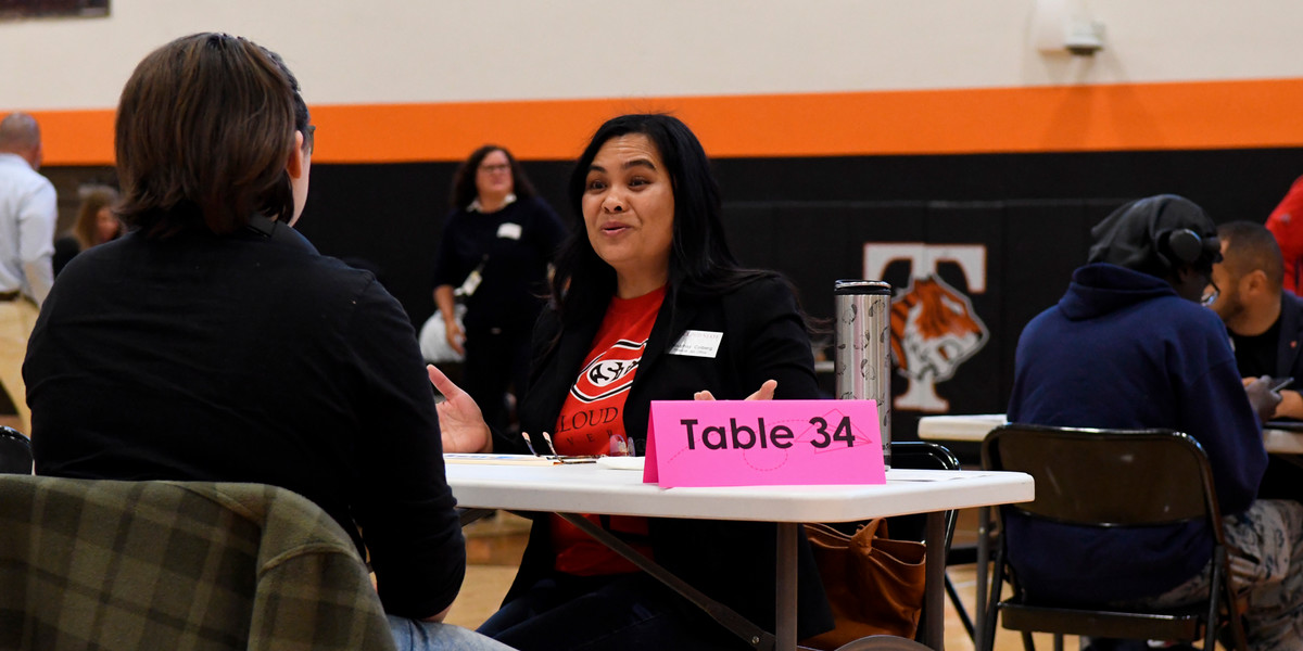 An SCSU volunteer speaks with a student in the Tech High School Gymnasium